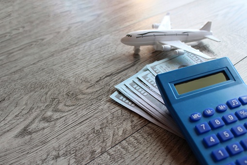 Toy plane, money and calculator on wooden table with copy space. Travel and transportation concept