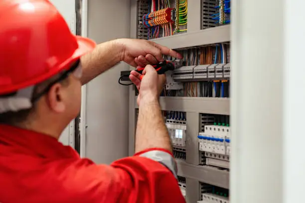 Photo of Electrical wiring repair. Repairman repairs electrical panel.