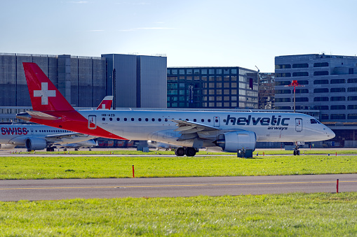 Scenic view of Zürich Airport with Helvetic Airways airplane Embraer E190 register HB-AZD at runway ready for takeoff on a sunny autumn day. Photo taken November 23rd, 2022, Zurich, Switzerland.