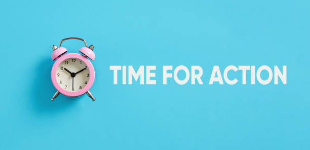 istock Pink alarm clock on blue background with the message time for action. 1456724499
