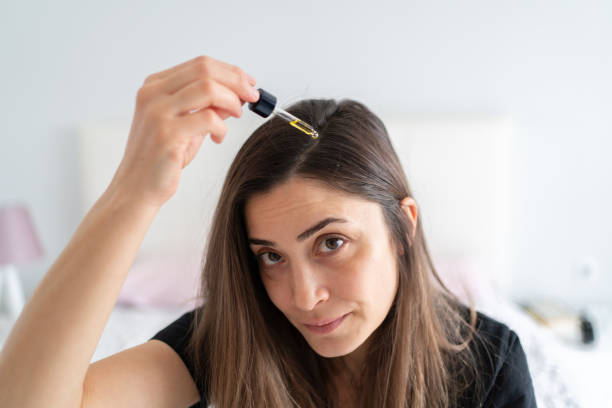 retrato de aplicar suero para el cabello a su cabello - cabello humano fotografías e imágenes de stock