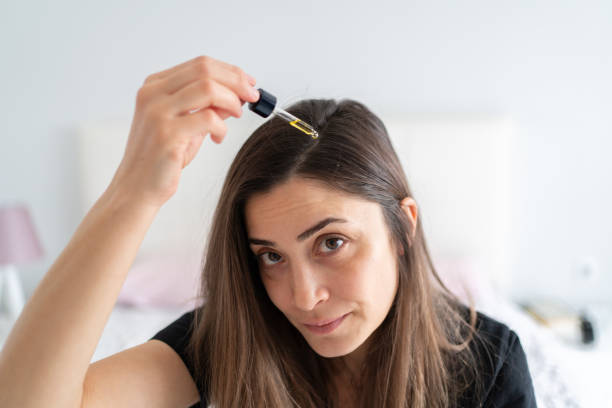 Portrait Of Applying Hair Serum To Her Hair Woman Applying Hair Serum To Her Hair dandruff stock pictures, royalty-free photos & images