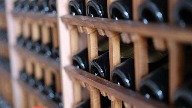 bouteilles de vin poussiéreuses empilées sur des étagères en bois au sous-sol - upper class food empty retro revival photos et images de collection