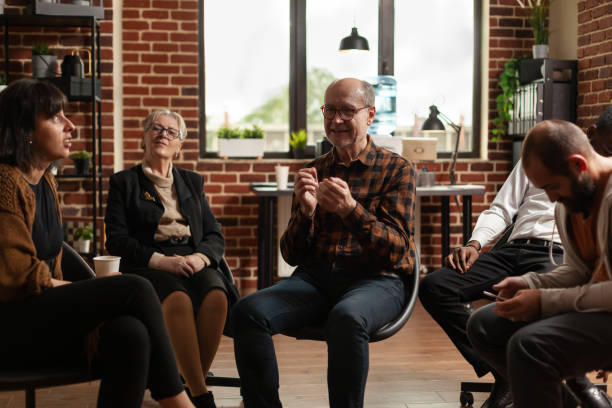 istock Senior man sharing addiction problems with group of people at aa meeting 1456728047