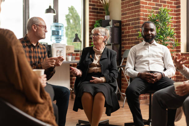 istock Woman psychiatrist having support conversation with people at aa group meeting 1456728203