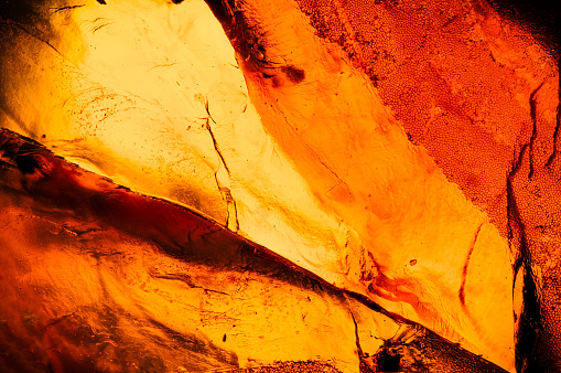 Amber macro abstract background texture, with inclusion detail, colorful yellow orange and red. unpolished rough raw specimen close-up