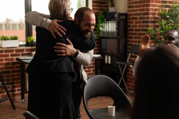 istock Man and psychologist hugging after sharing addiction progress with aa meeting group 1456730612