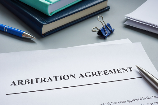 Papers with arbitration agreement and pen.