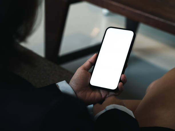 istock White blank screen on mobile phone vertical style in business woman's hands who wearing formal suit, relaxed sit with cross legs on couch in cozy living room. Empty mock-up screen smartphone. 1456733740