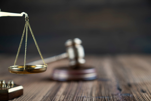 Gavel and scale on rustic brown planks.