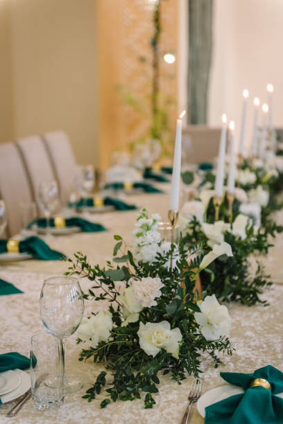 istock Wedding set up, dinner table reception. A plate with a green cloth towel, knives and forks next to the plate. Flower composition with eucalyptus leaves in the center of the table and burning candles. 1456739925