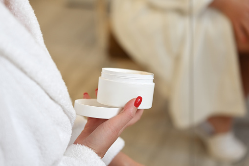 woman's hand holding Cosmetics product in a white bottle with body cream. copy space.