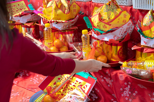 Asian mother and daughter buying fruits from local shop for make offerings to the spirits at shrine during Chinese New Year festive.