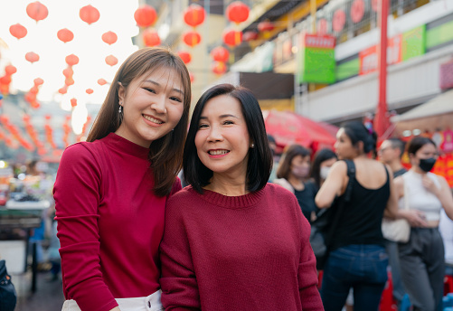 Happy Asian woman using phone taking selfie with mother at Yaowarat road on Chinese New Year holiday.