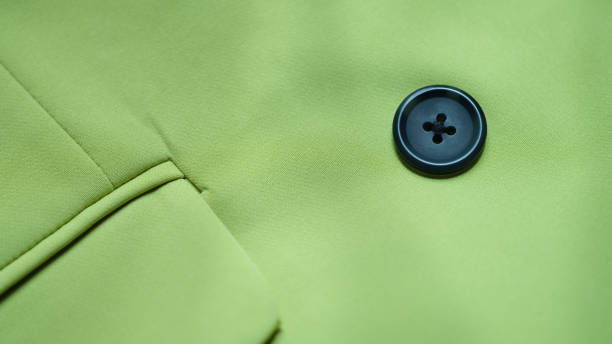 Black button is sewn on green cotton fabric closeup Black button is sewn on green cotton fabric closeup. Buttons for clothes features and selection coat wool button clothing stock pictures, royalty-free photos & images