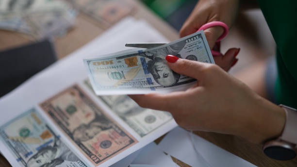 istock Criminal cuts dollar bills with scissors printed on printer closeup 1456745179