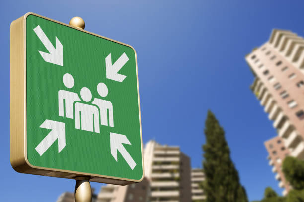 Emergency assembly point. Closeup of a green sign in a city against a clear blue sky. Outdoor sign indicating where people should congregate following an emergency evacuation of the building.