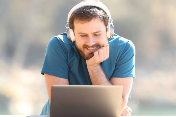istock Happy man with headphones watching laptop content 1456747763