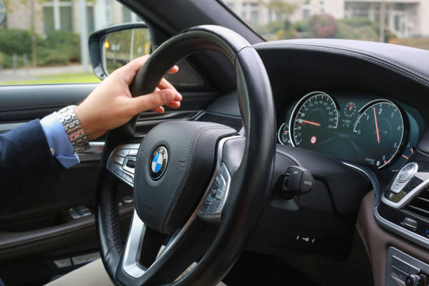 el hombre está conduciendo un coche en la ciudad.  panel de la consola central del bmw serie 7, primer plano del volante del automóvil. - bmw fotografías e imágenes de stock