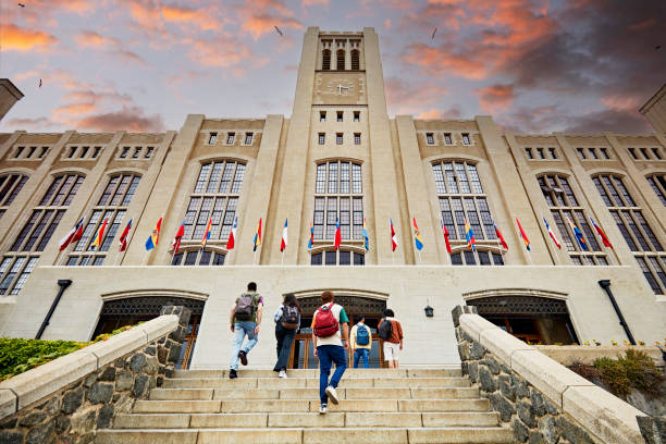 College students arriving for night school Low angle view of men and women with backpacks walking up staircase to building entrance with dramatic sunset sky overhead. Property release attached. campus stock pictures, royalty-free photos & images