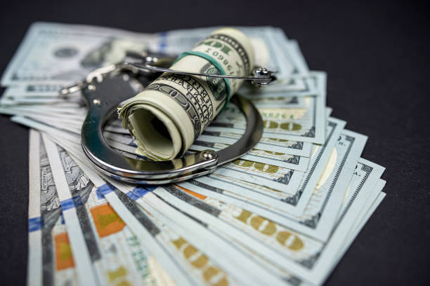 istock Handcuffs rest on hundred dollar American bills. 1456750236