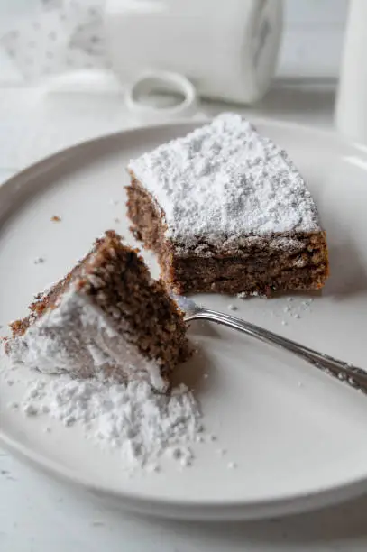 Traditional italian torta caprese. Baked with grated almonds and real dark chocolate. Topped with powdered sugar and served slicee on a white plate