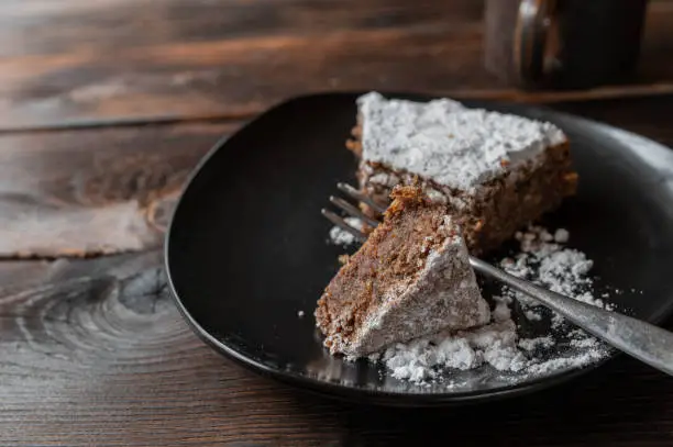 Italian chocolate almond cake. Served on a rustic plate with fork and cross section view on dark wooden table background. Traditional torta caprese. Side view, closeup and front view with space for text