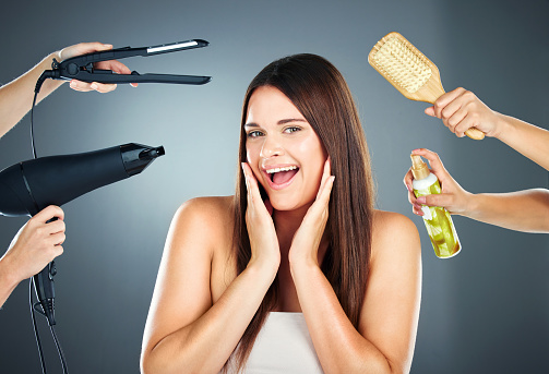 Hair, tools and portrait of woman with haircare products for beauty, cosmetology and wellness on a grey studio background. Brush, hairdryer and spray for hairstyle and hair treatment in a salon