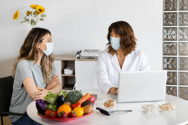 istock Dietitian and patient in sterile masks talking in office 1456753695