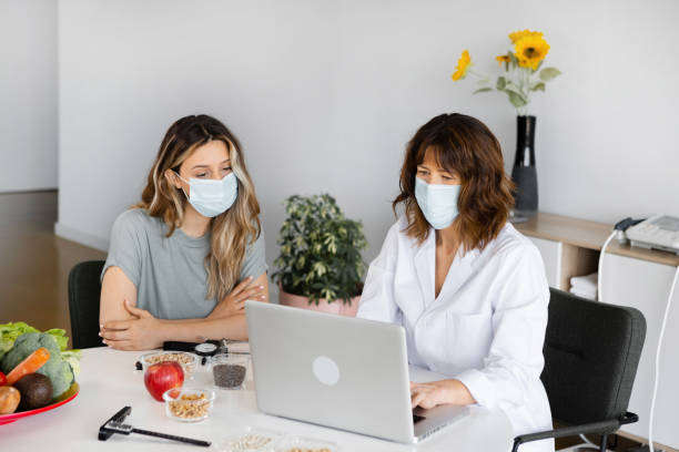 istock Dietitian and patient in sterile masks talking in office 1456753702