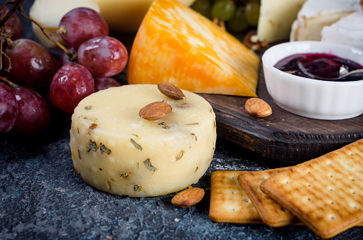 Elegant cheese selection featuring brie, blue cheese, and cheddar, served with honey, walnuts, and green grapes.