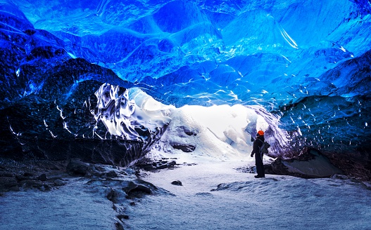 Traveler in ice cave, man standing underground inside of a glacier, climate specific, Vatnajokull National Park, amazing nature of Skaftafell, Iceland