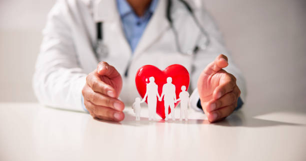 istock Doctor's Hand Protecting Red Heart With Family Figure 1456758912