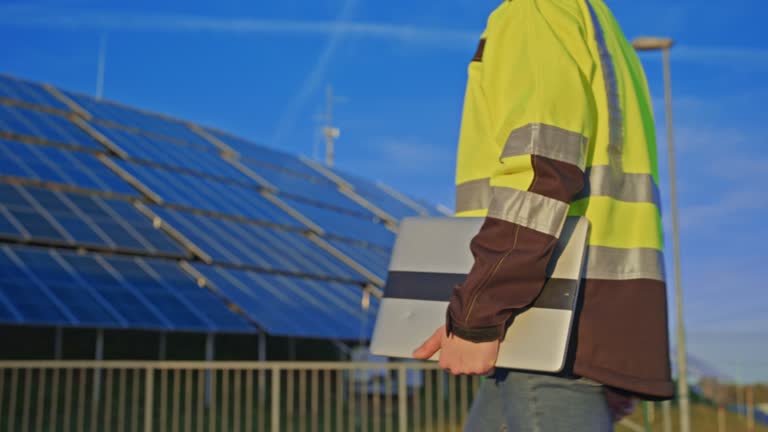 SLO MO Young engineer carries a laptop while he walks to the photovoltaic power station