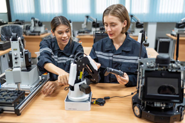 menina engenheira sentada na sala de fabricação do robô verificando a placa de controle eletrônico - efficiency complexity cooperation gear - fotografias e filmes do acervo