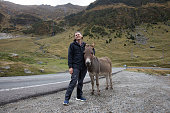 sporty guy tourist hugged a donkey near the road in the mountains
