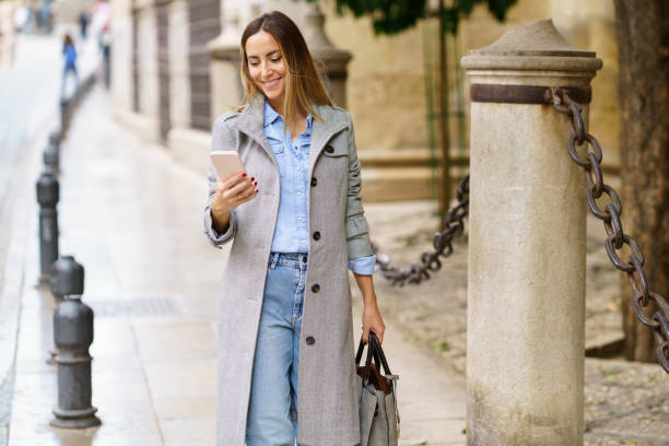 istock Woman in coat using smartphone on street 1456767087