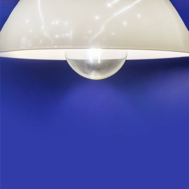 modern chandelier hangs against blue wall. Dim lamp light. hanging lamp, decor for room, office. Selective focus, text space, copy space