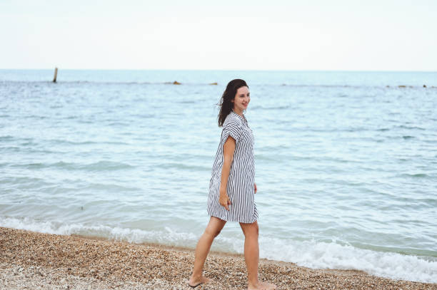 istock Young woman standing on the shore at the beach 1456768538