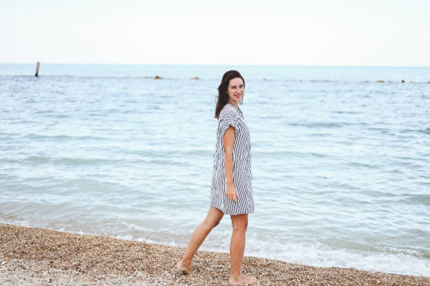 istock woman in a drees walking alone on sandy beach at summer sunset 1456768550