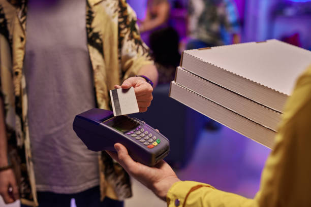 młody człowiek płacący kartą kredytową za zamówioną pizzę trzymaną przez dostawcę - two party system zdjęcia i obrazy z banku zdjęć