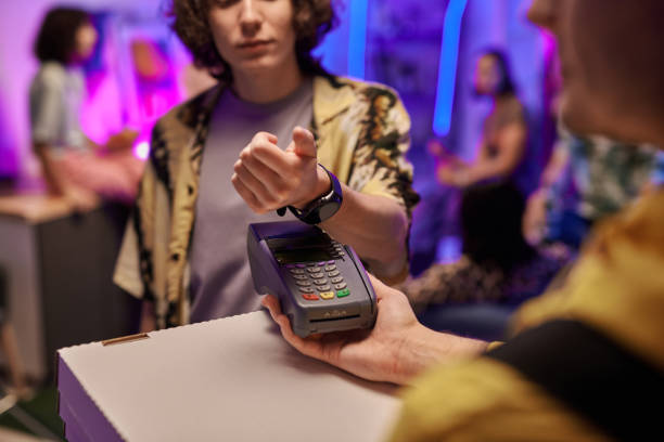 main du gars avec smartwatch sur terminal de paiement et boîtes avec pizza - two party system photos et images de collection