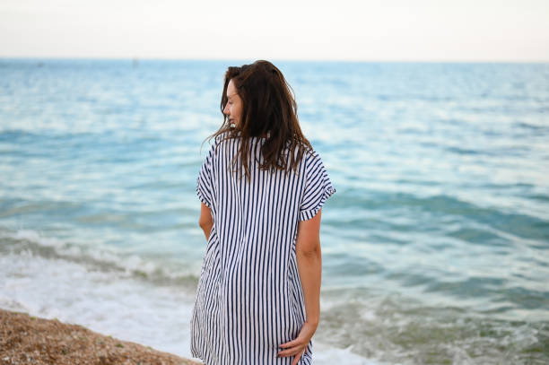 istock Rear view of a woman walking on sandy beach . 1456768676