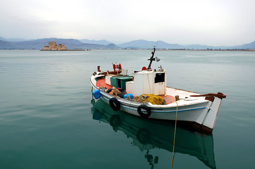 A fishing boat in the pretty harbor in Nafplio or Nauplia, Greece.  Bourtzi Castle is in the background. Nafplio is an old town in Peloponnese Greece.