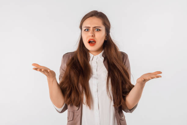 istock What's wrong. Confused beautiful woman spreads hands sideways, smirks face, feels doubt while makes choice, stand with with confused look against white studio background 1456770206