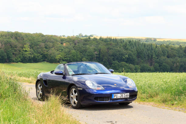 niebieski roadster porsche boxster 986 z panoramą gór hunsrück. samochód jest dwumiejscowym samochodem sportowym z centralnie umieszczonym silnikiem produkowanym przez niemiecką firmę motoryzacyjną porsche. - germany landscape nissan roadster zdjęcia i obrazy z banku zdjęć