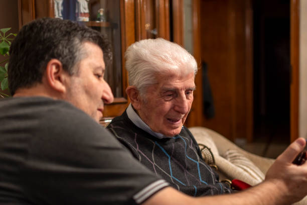 istock Smiling senior man with son sitting on sofa 1456771008