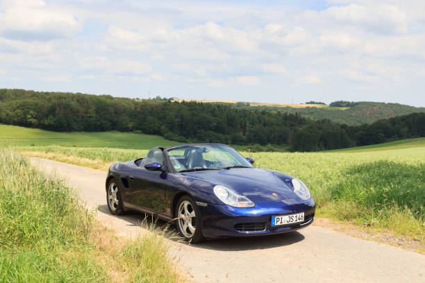 roadster azul porsche boxster 986 con panorama de montaña de hunsrück. el automóvil es un automóvil deportivo biplaza de motor central fabricado por la compañía automotriz alemana porsche. - germany landscape nissan roadster fotografías e imágenes de stock