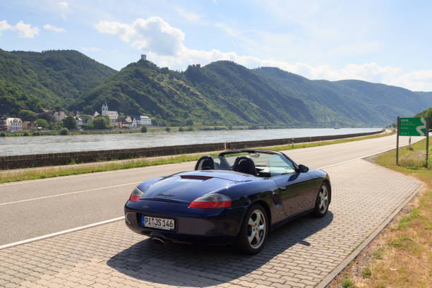 roadster azul porsche boxster 986 con garganta del río rin y panorama del castillo. el automóvil es un automóvil deportivo biplaza de motor central fabricado por la compañía automotriz alemana porsche. - germany landscape nissan roadster fotografías e imágenes de stock