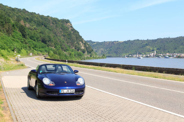 niebieski roadster porsche boxster 986 z panoramą wąwozu renu. samochód jest dwumiejscowym samochodem sportowym z centralnie umieszczonym silnikiem produkowanym przez niemiecką firmę motoryzacyjną porsche. - germany landscape nissan roadster zdjęcia i obrazy z banku zdjęć